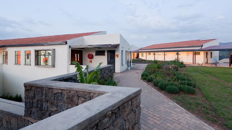 Photo of Butaro District Hospital, Photo by Iwan Baan, Back Entrance of Butaro Hospital with Low Masonry Wall